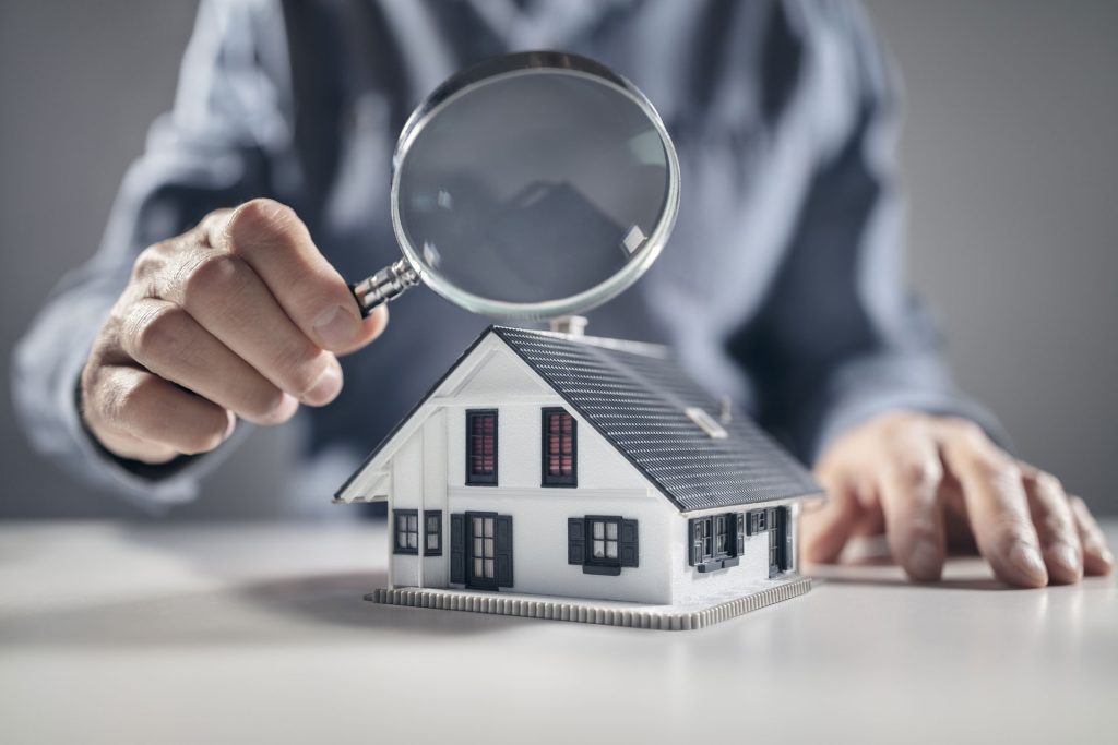 person holding magnifying glass looking at home